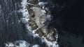 Top view of beautiful reef with waves and lighthouse. Clip. Single lighthouse on rocky ledge in blue sea on sunny day