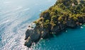 Top view of a beautiful sea coast with a white lighthouse, green trees and palm trees on top of a cliff surrounded by sea water