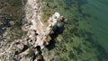 Top view of beautiful stone shore. Action. Rocky coast with rocks and clear water on sunny day. Exciting drone flight