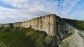 Top view of beautiful white rock with green grass on background of blue sky. Shot. Panorama of white cliff with green