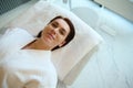 Top view of a beautiful woman with perfect glowing skin lying down on a massage table in a spa room, relaxing while receiving a Royalty Free Stock Photo