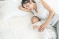 Top view of beautiful young Asian mom and her cute little baby sleeping in bed at home Royalty Free Stock Photo