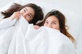 Beautiful young asian women lesbian happy couple showing surprise and looking at camera while lying in bed under blanket. Royalty Free Stock Photo