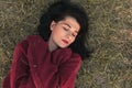 Top view of beautiful young Caucasian woman smiling and closed eyes, wearing knitted pullover, lying on the grass Royalty Free Stock Photo