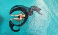 Top view of beautiful young sexy dark-haired woman floating flying weightless elegant in erotic dream turquoise water of the pool