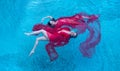 Top view of a beautiful young sexy dark-haired women relaxed in red dress floating weightlessly elegant in the water of the pool, Royalty Free Stock Photo