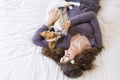 top view of a beautiful young woman lying on bed with her cute small dog besides. Dog wearing bowtie. Home, indoors and lifestyle Royalty Free Stock Photo
