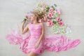 TOP VIEW: Beautiful young woman in a pink dress lies on a floor with a flowers