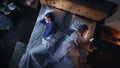 Top View Bedroom Apartment: Man Uses Smartphone in Bed at Night When His Female Partner Trying to