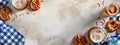 Top view of beers and pretzels on a rustic table with blue checkered cloths.