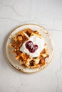 Top view Belgian cottage cheese waffles with sour cream and cherry jam on a plate on a concrete white background. Sweet