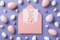 Top view of big pink envelope with card and paper rabbit inside many wonderful multicolored Easter eggs different size on the Royalty Free Stock Photo