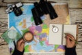 Top view of binoculars, compass, retro photo camera, coffee and map on a white wooden table