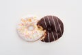 Top view of bitten chocolate and white doughnuts connected on white background .