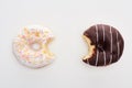 Top view of bitten chocolate and white doughnuts on white background .