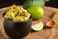 Top view of black bowl with guacamole on wood with lime, avocado and spoon, selective focus, Royalty Free Stock Photo