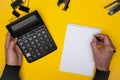 Top view of black calculator and pen in man sleeve up hands writing in notepad Royalty Free Stock Photo