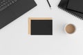 Top view of a black card mockup and envelope with a laptop, cup of coffee and workspace accessories on a white table