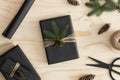 Top view of a black christmas gifts surrounded with pine cones, leaves and twine on a wooden table