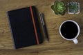 Top view of black closed cover blank notebook with coffee cup and pen Royalty Free Stock Photo