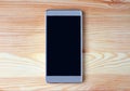 Top view of a black empty screen smartphone isolated on light brown wooden table Royalty Free Stock Photo