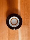 Top view of a black espresso machiatto cup on a wooden table