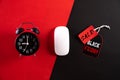 Top view of Black Friday Sale text with black gift box with Alarm clock, white mouse and red paper tag on red black background.