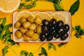 Top view of black and green olives assortment in bowl on yellow background with lemons and herbs Royalty Free Stock Photo