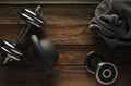 Top view of black iron kettlebell, dumbbell and grey towel on wooden floor Sport background with copyspace