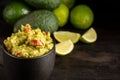 Top view of black jar with guacamole on dark table with sliced limes and avocados, horizontal Royalty Free Stock Photo