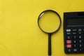 Top view black magnifying glass and calculator on yellow background.Business and finanse concept