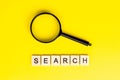 Top view of black magnifying glass with the word search on light yellow background. Royalty Free Stock Photo