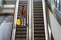 Top view of Black man with yellow luggage standing on escalator at airport terminal wearing face protective mask during virus Royalty Free Stock Photo