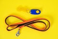 Top view of black orange collar or leash, blue clicker for a dog on a yellow background. Necessary for a walk or training tool set Royalty Free Stock Photo