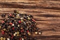 Top view on black, red and white peppercorns on wooden background, shallow depth of field.