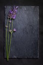 Top view of a black slate board with a bunch of lavender flowers on a dark background