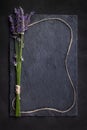 Top view of a black slate board with a bunch of lavender flowers tied with a brown string, which is placed around as a frame. Royalty Free Stock Photo