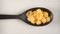 TOP VIEW: Black spoon with figural pasta conchiglie