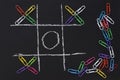Top view tic tac toe adn stationary clips on the black background