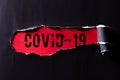 Top view of Black torn paper and the text COVID-19 on a red background. Healthcare and medical concept