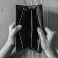 Top view black and white image of woman`s hands open an empty black leather wallet with wooden table Royalty Free Stock Photo