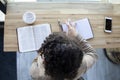 Top view of Black woman studies her bible and uses phone