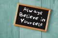 Top view of blackboard with the phrase always believe in yourself, over wooden background