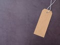 Top view, blank brown cardboard label or tag tied with string on dark grey background. Royalty Free Stock Photo