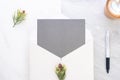 Top view of blank grey card in white envelop with coffee and pin