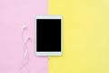 Top view of an blank mock up tablet and earphone on pink and yellow pastel color screen with copy space. Royalty Free Stock Photo