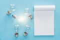 Top view of blank notebook with light bulbs on blue background, Royalty Free Stock Photo