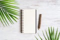 Top view of blank notebook with palm leaf and wooden pencil on grunge white wood background, flat lay with copy space for your Royalty Free Stock Photo