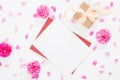 Top view blank paper card, red envelope, gift box, rose flowers buds and petals on white background. Minimal flat lay style Royalty Free Stock Photo