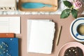 Top view of blank paper and gold pen placed on table with pink rose, coffee cup, feather shape pen and empty postcard